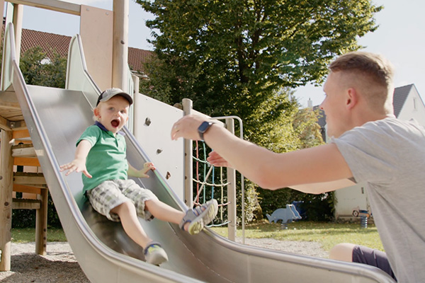 Mitarbeiter verbringt Freizeit mit Kind auf Spielplatz